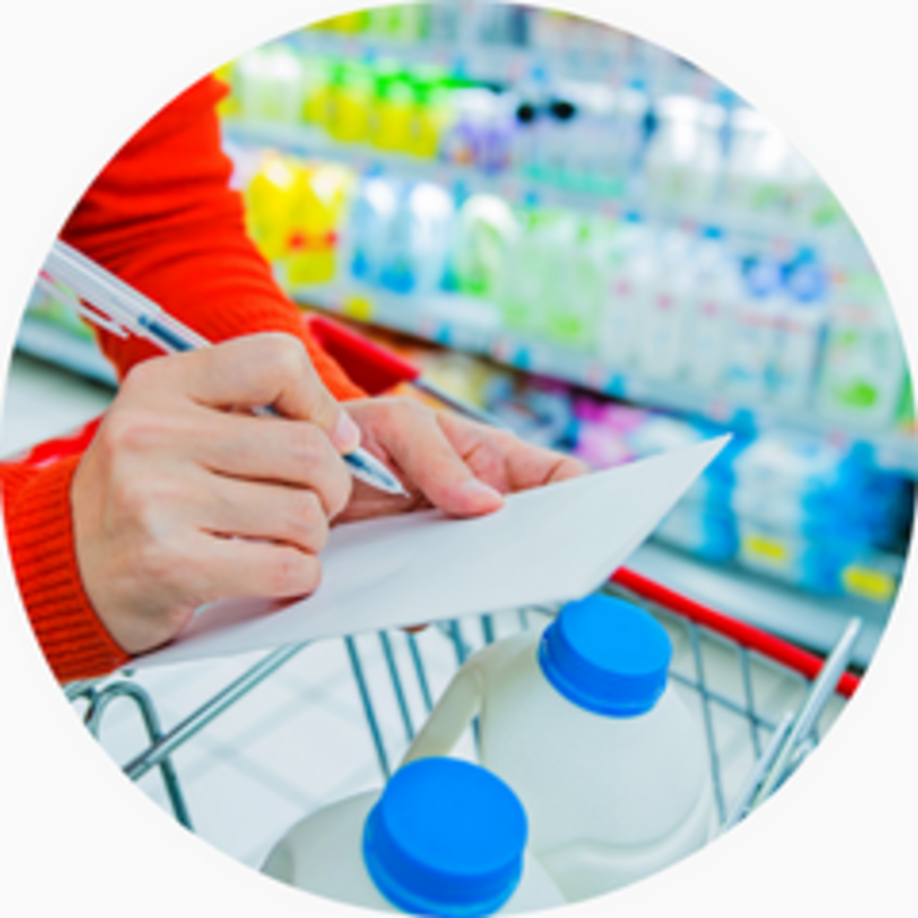 A shopper writes a list while comparing products in a grocery store.