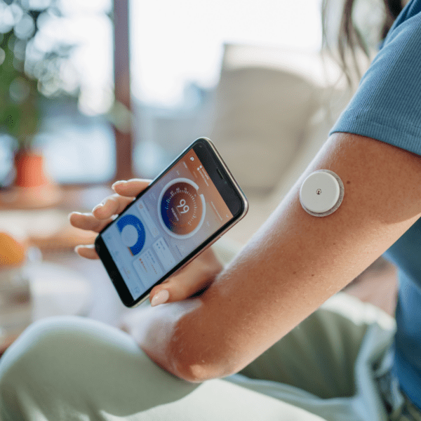 Person checks readings from an arm-worn continuous glucose monitor on a smartphone