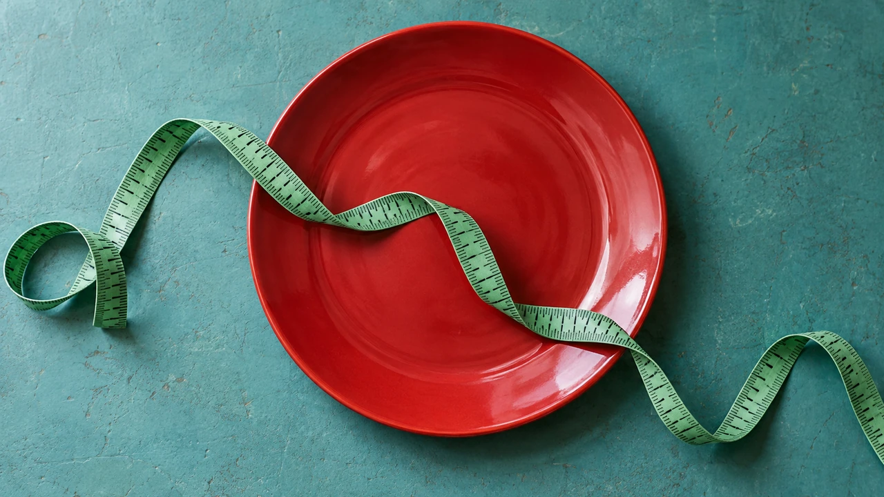 A red plate with a loosely draped green measuring tape.